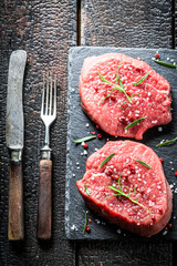 Raw beef with rosemary and pepper on a stone plate