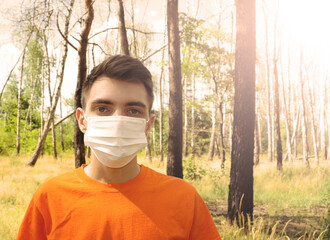 Young man in a white mask in a pine forest. Sunset