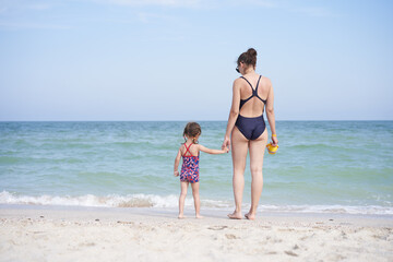Mother daughter beach together rear view Unrecognizable caucasian woman little girl swimwear standing seaside back.