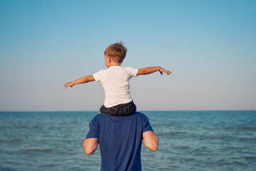 Father son together outside showing finger sea horizon back Man child spending time vacation enjoying summer