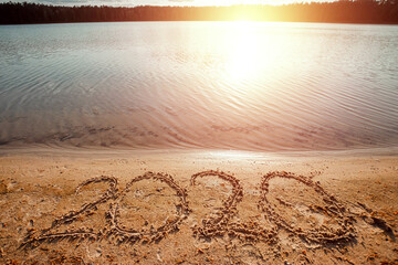 Happy New Year lettering 2020 on the beach. Holiday concept, vacations.