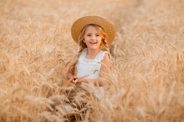 Naklejka na ściany i meble A little blonde girl holds a basket of bread in a wheat field. environmentally friendly farm products. wheat harvest