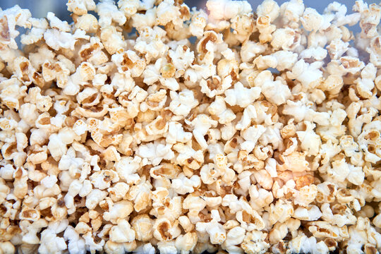 Popcorn background behind glass in a po pcorn maker.