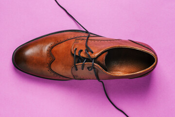 Brown shoes on a colored background with untied laces. Fashionable classic leather shoes. Men's...