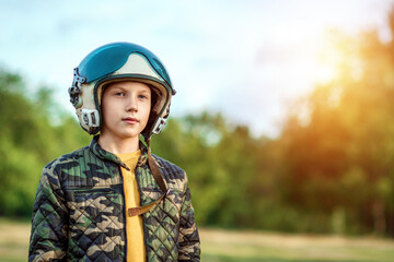 A boy in a pilot's helmet on a background of greenery. Dream concept, choice of profession, game. Copy space.