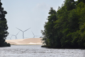 Vegetation and a wind farm in the middle of the sand dunes, in Lençóis Maranhenses. The picture was taken from a boat in Preguiças River. Maranhão, Brazil.