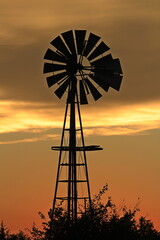 windmill at sunset with colorful clouds in Kansas.