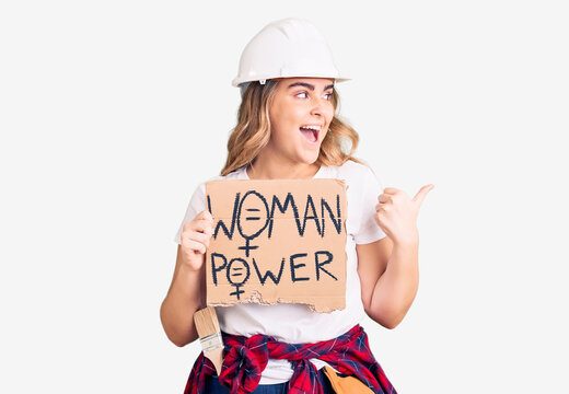 Young caucasian woman holding woman power banner pointing thumb up to the side smiling happy with open mouth