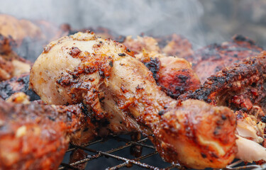 Grilled chicken thigh on a grid with smoke in the background, close-up side view.