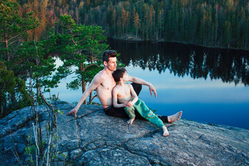 middle age man with little cute son doing sport yoga on the top of the mountain together, happy family lifestyle people outdoor, summer wild nature for training