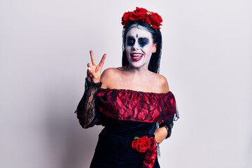 Young woman wearing mexican day of the dead makeup smiling with happy face winking at the camera...
