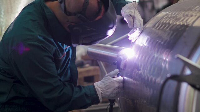 Welder, using VIG, TIG, MIG MAG method to welding stainless steel parts, close up. The welder uses a mask to protect your eyes. Argon welding of stainless steel sheet, parts. Scene N.