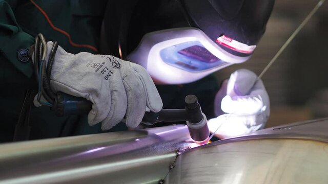 Welder, using VIG, TIG, MIG MAG method to welding stainless steel parts, close up. The welder uses a mask to protect your eyes. Argon welding of stainless steel sheet, parts. Scene F.