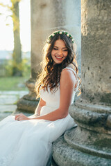 Happy beautiful young bride outside on a summer meadow at the sunset