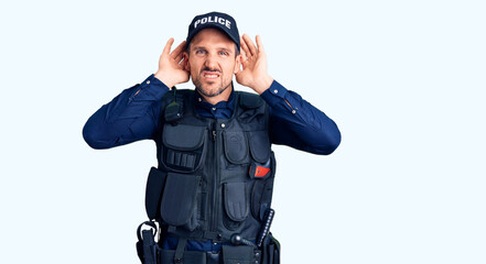Young handsome man wearing police uniform trying to hear both hands on ear gesture, curious for gossip. hearing problem, deaf