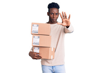 Young african american man holding delivery package with open hand doing stop sign with serious and confident expression, defense gesture