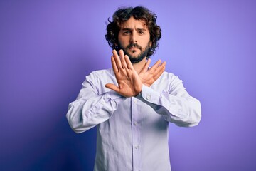 Young handsome business man with beard wearing shirt standing over purple background Rejection expression crossing arms doing negative sign, angry face