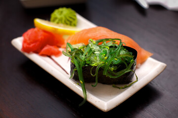 Sushi set, chukka seaweed, fresh salted salmon, lemon and ginger, on a white plate