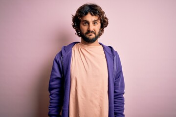 Obraz premium Young handsome sporty man with beard wearing casual sweatshirt over pink background skeptic and nervous, frowning upset because of problem. Negative person.