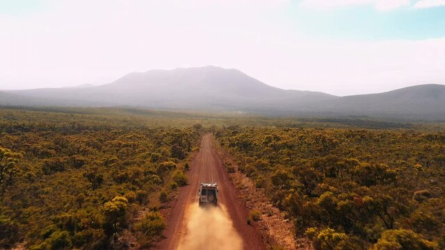 Aerial, drone shot following a 4x4 car, driving on a red sand, desert road, sunny day, in Hassell National Park, West Australia