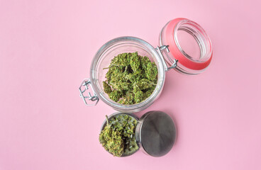Medical Marijuana Jar flower buds and weed Grinder on pink background