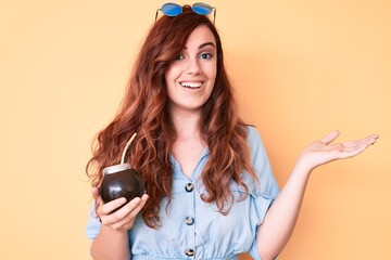 Young beautiful woman drinking mate infusion celebrating achievement with happy smile and winner...