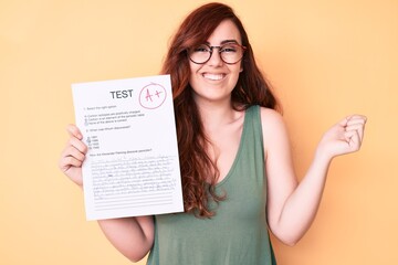 Young beautiful woman showing a passed exam screaming proud, celebrating victory and success very excited with raised arm