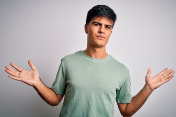 Young handsome man wearing casual t-shirt standing over isolated white background clueless and...