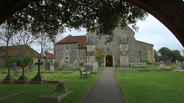 Looking through the arch of a lychgate into the churchyard of St Margaret's Church, Rottingdean, East Sussex