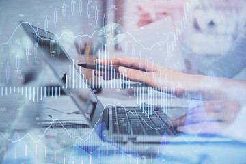 Multi exposure of woman hands typing on computer and financial graph hologram drawing. Stock market analysis concept.