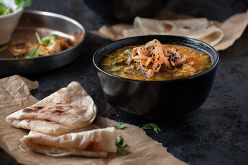 Vegan split yellow pea soup with caremelized onions, flat breads.  Black background, copy space