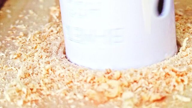 Rotating Hole Saw With Drill Bit Making Hole On A Piece Of Wood - close up slowmo