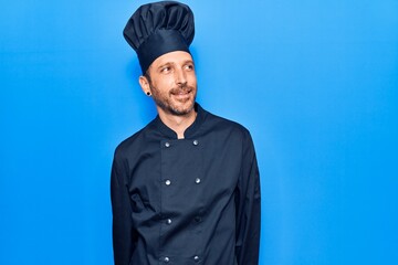 Young handsome man wearing cooker uniform looking to side, relax profile pose with natural face and confident smile.