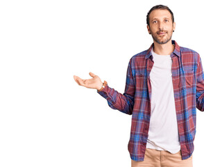 Naklejka premium Young handsome man wearing casual clothes smiling showing both hands open palms, presenting and advertising comparison and balance