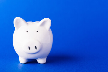 Front small white fat piggy bank, studio shot isolated on dark blue background and copy space for use, Finance, deposit saving money concept