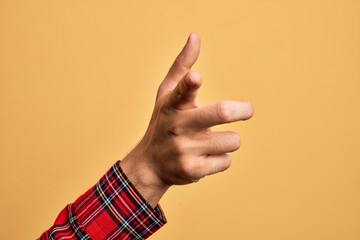 Hand of caucasian young man showing fingers over isolated yellow background pointing forefinger to the camera, choosing and indicating towards direction