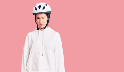 Beautiful brunette young woman wearing bike helmet and sporty clothes depressed and worry for distress, crying angry and afraid. sad expression.