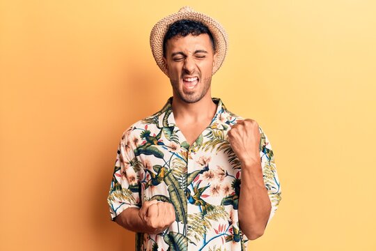 Young hispanic man wearing summer hat celebrating surprised and amazed for success with arms raised and eyes closed
