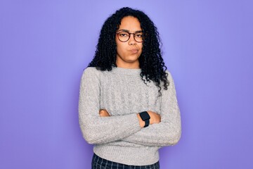 Young african american woman wearing casual sweater and glasses over purple background skeptic and nervous, disapproving expression on face with crossed arms. Negative person.