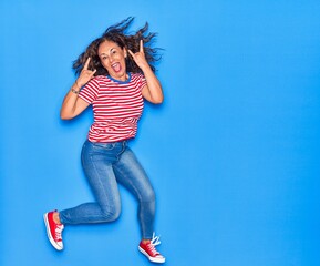 Middle age beautiful hispanic woman wearing casual clothes smiling happy. Jumping with smile on face over isolated blue background