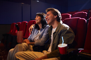 Portrait of smiling young couple in cinema watching movie together and embracing while enjoying romantic date, copy space