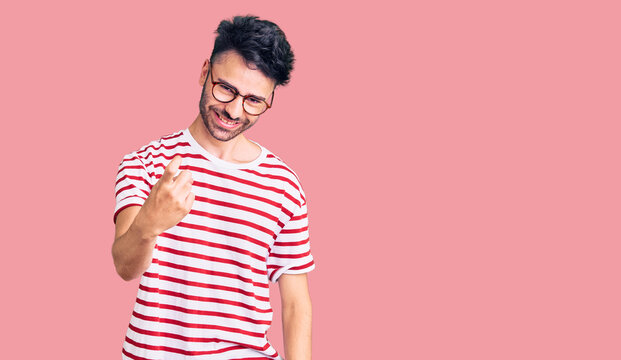 Young hispanic man wearing casual clothes beckoning come here gesture with hand inviting welcoming happy and smiling