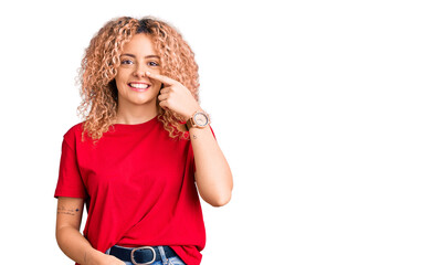 Young blonde woman with curly hair wearing casual red tshirt pointing with hand finger to face and nose, smiling cheerful. beauty concept