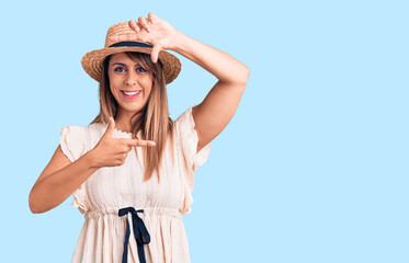 Obraz na płótnie Canvas Young beautiful woman wearing summer hat and t-shirt smiling making frame with hands and fingers with happy face. creativity and photography concept.