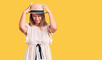 Young beautiful woman wearing summer hat and t-shirt suffering from headache desperate and stressed because pain and migraine. hands on head.