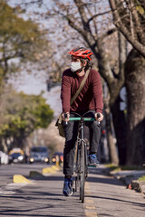 Young man on bicycle with protective mask against covid 19 driving on bike lane