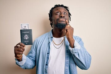 Young african american tourist man holding passport with dollars banknotes as money travel serious...