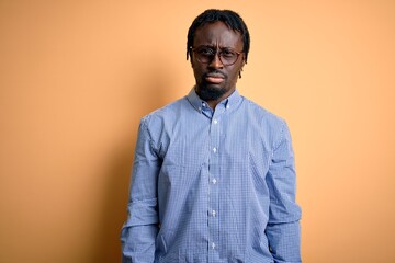 Young handsome african american man wearing shirt and glasses over yellow background skeptic and nervous, frowning upset because of problem. Negative person.