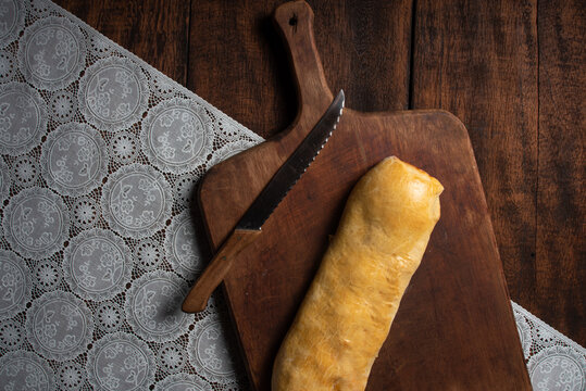 Homemade bread stuffed with shredded chicken on rustic wood and knife with black background, top view