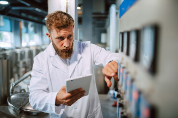  Professional caucasian handsome technologist expert in white uniform standing in pharmaceutical or food factory  - production plant checking productivity and quality using tablet computer.